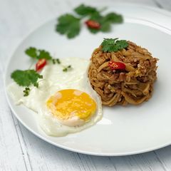 A picture of Thai style egg noodles stir-fry served with fried egg.