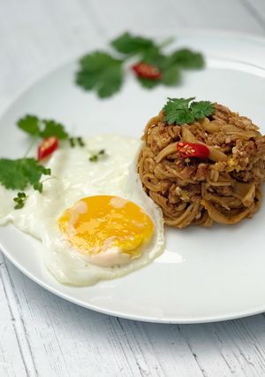 A picture of Thai style egg noodles stir-fry served with fried egg.