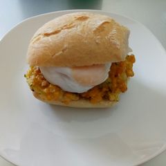 A picture of Veggie fritters and poached egg in a bun.