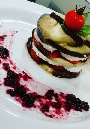 Una foto de Berenjenas asadas en láminas con tomate y rulo de cabra