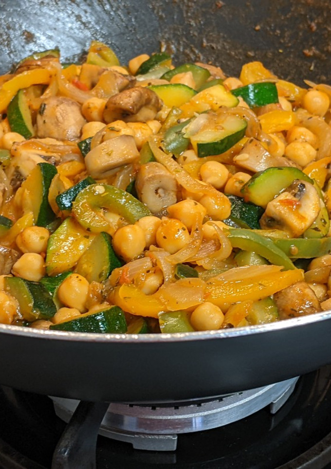 Una foto de Wok de verduras en su jugo con champiñones y garbanzos