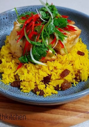 A picture of Yellow Rice With Raisin Serve With Frypan Fish Barramundi Fillet.