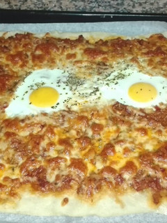 Una foto de Pizza de masa fina con huevo, atún y jamón serrano