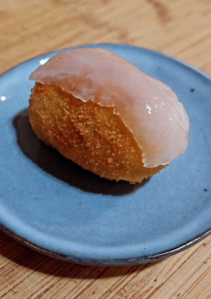 Una foto de Croquetas de pollo especiado en salsa con acelgas con velo de panceta ibérica