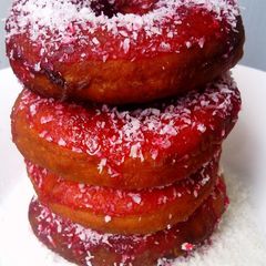 A picture of Red Glazed Eggless Doughnuts with Coconut.