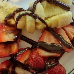 A picture of Strawberries & Bananas topped with chocolate syrup.