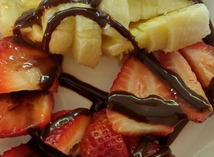 A picture of Strawberries & Bananas topped with chocolate syrup.