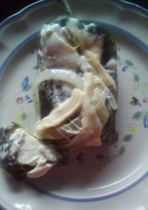 Una foto de Chiles poblano relleno acompañado de crema