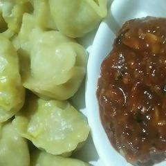 A picture of Veg momos with red tomato chilli chutney.
