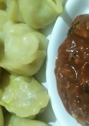 A picture of Veg momos with red tomato chilli chutney.