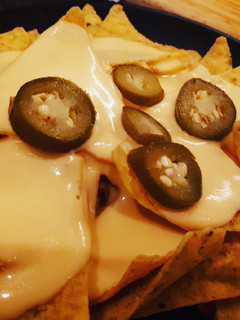 Una foto de Nachos con salsa cheddar
