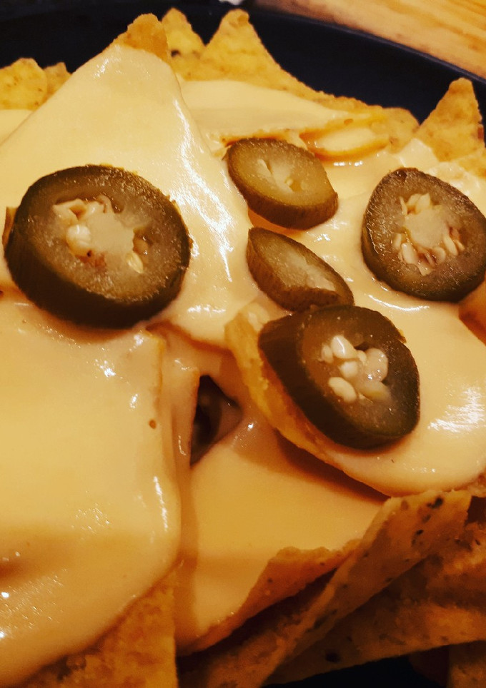 Una foto de Nachos con salsa cheddar