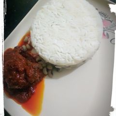 A picture of Rice/beans with palm oil stew.