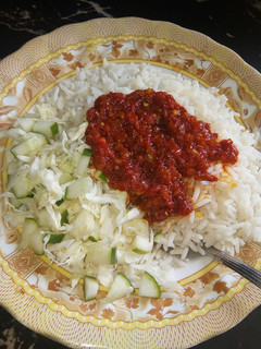 A picture of Rice and stew with cabbage and cucumber.