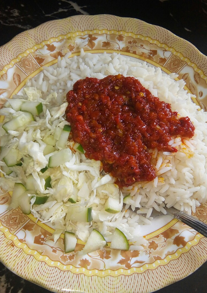 A picture of Rice and stew with cabbage and cucumber.