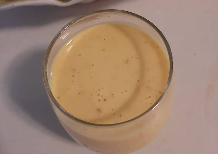Mango banana smoothie with a hand full of nuts