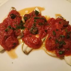 A picture of Sea bass with tomato and olive sauce.