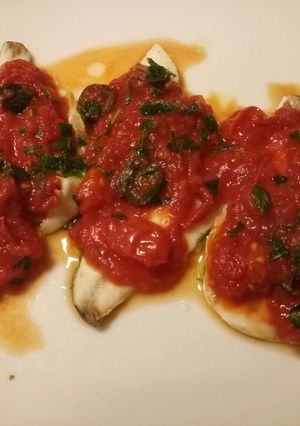 A picture of Sea bass with tomato and olive sauce.