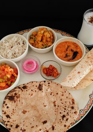 A picture of NORTH INDIAN THALI For lunch mutter -paneer, aloo gobhi, moong dal tadka,jeera rice,pickle, roti.