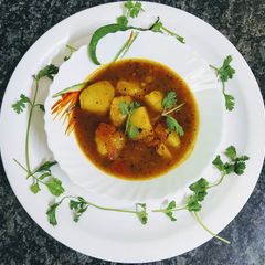 A picture of Aloo tamatar curry with instant rice dosa.