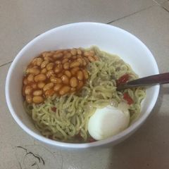 A picture of Noodles with boiled egg and baked beans.