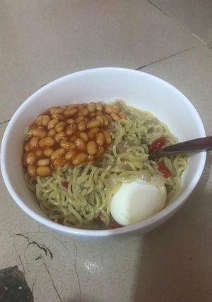 A picture of Noodles with boiled egg and baked beans.