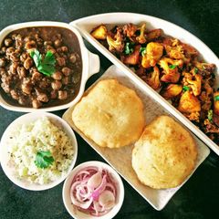 A picture of Chole, Bhature, Jeera Rice and Aloo Gobhi.