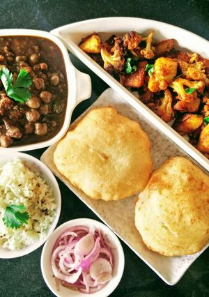 A picture of Chole, Bhature, Jeera Rice and Aloo Gobhi.