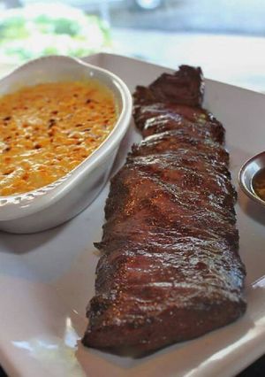 Una foto de Churrasco acompañado de crema de maíz gratinado y salsa de pimentón