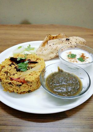 A picture of Lots of vegetables tehiri with green chutney,curd,Pappas,salad.