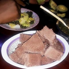 A picture of Brown ugali with veggies and meat.