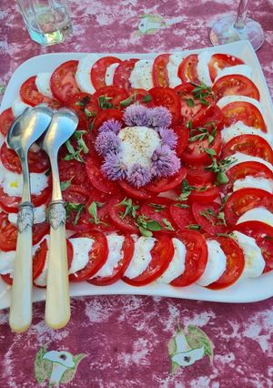 Une photo de Salade de tomates à la mozzarella, basilic et fleurs de ciboulette