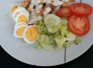 Una foto de Pechuga de pollo bañada en salsa de queso con ensalada y huevo duro