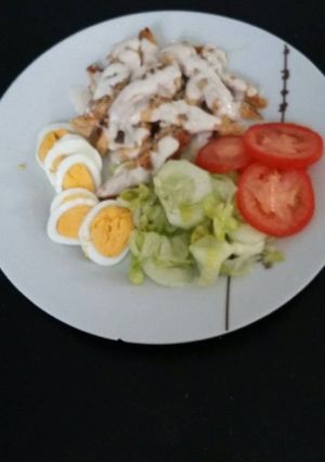 Una foto de Pechuga de pollo bañada en salsa de queso con ensalada y huevo duro