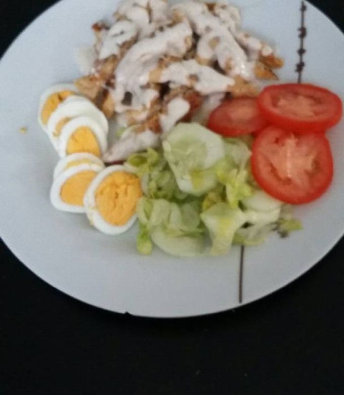 Una foto de Pechuga de pollo bañada en salsa de queso con ensalada y huevo duro