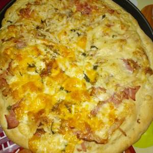 Pizza de jamón de york bacon con doble quesos variados con albahaca a la piedra