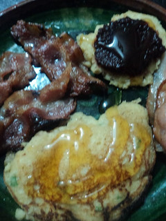 Una foto de Hot cakes navideños con albahaca y amaranto, acompañados de tocino, miel y mermelada de chile correa