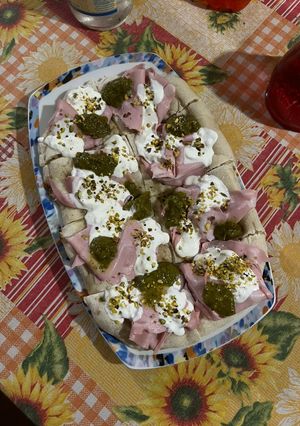A picture of Gourmet Pinsa with Mortadella, Pistachio Pesto, Stracciatella, and Chopped Pistachios.