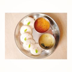 A picture of Idli with sambhar and chutney.