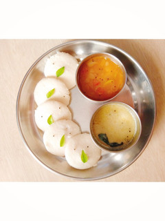 A picture of Idli with sambhar and chutney.