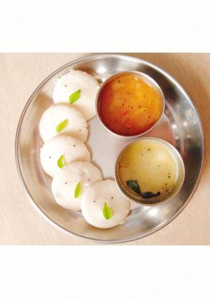 A picture of Idli with sambhar and chutney.