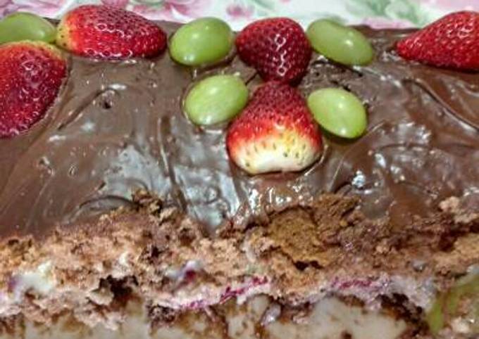 Bolo com cobertura de chocolate e decorados com morangos, uvas e