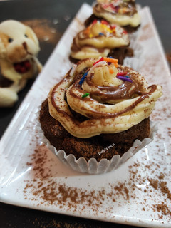 A picture of Chocolate cup cake with vanilla butter cream and chocolate sauce.