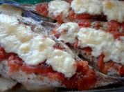 Una foto de filet de merluza al horno con vegetales