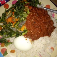 A picture of Rice and stew with vegetables and boiled egg.