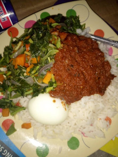A picture of Rice and stew with vegetables and boiled egg.