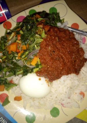 A picture of Rice and stew with vegetables and boiled egg.