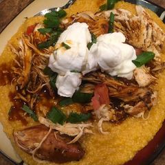 A picture of Shredded barbecue chicken over grits.