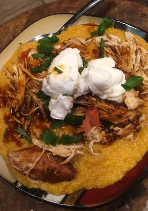 A picture of Shredded barbecue chicken over grits.