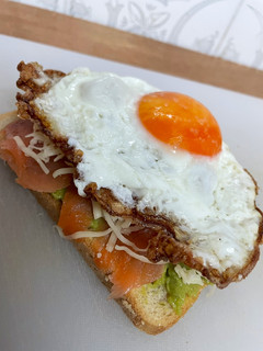 Una foto de Tosta de guacamole, salmón ahumado y huevo frito